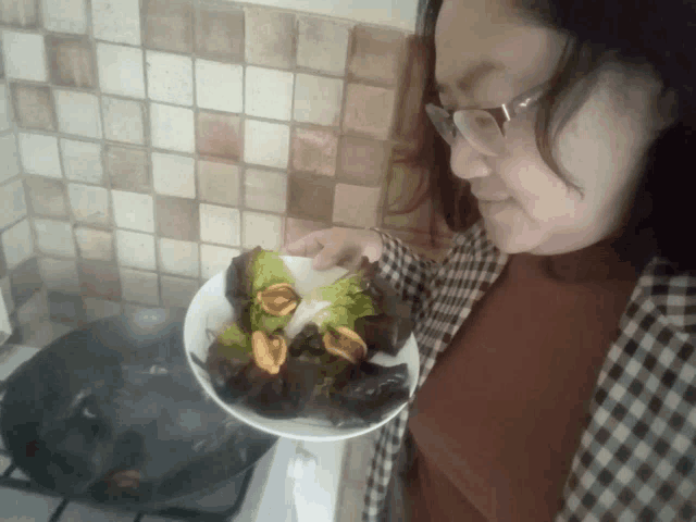 a woman with glasses holds a plate of food in her hand