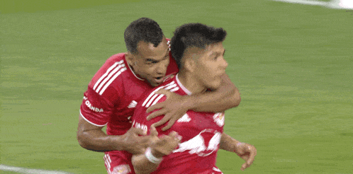 two soccer players are hugging each other and one has a red bull on his jersey