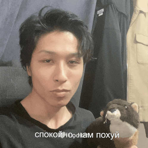 a man holding a stuffed animal with a foreign language caption