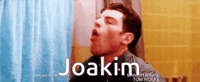 a man is yawning in front of a blue shower curtain with the name joakim written on the bottom