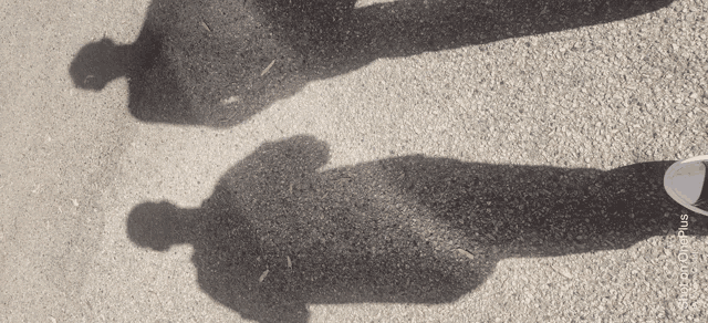 two people 's shadows on a gravel road with the words photoplus on the bottom