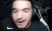 a man wearing headphones is sitting in a chair with his eyes closed and his mouth open .