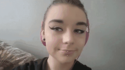 a young girl wearing pink headphones is taking a selfie while sitting on a couch .