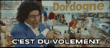 a man in a blue suit is standing in front of a sign that says " dordogne "