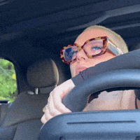 a woman wearing glasses is sitting in a car