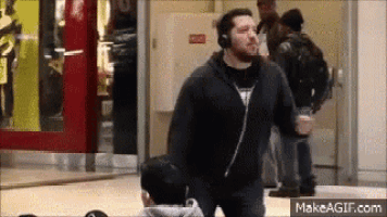 a man wearing headphones is dancing in a mall while another man watches .
