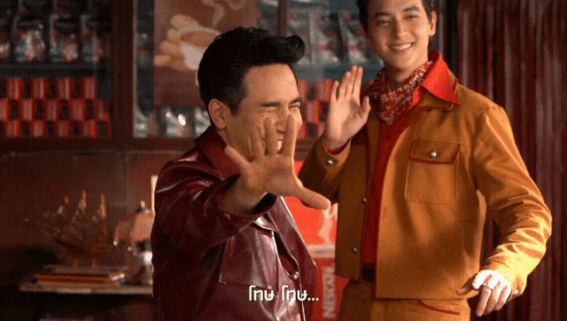 two men are standing next to each other and one of them has the word nescafe on his jacket