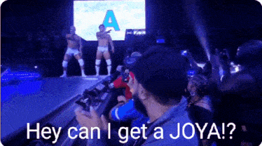a man taking a picture of a wrestling match with the words hey can i get a joya