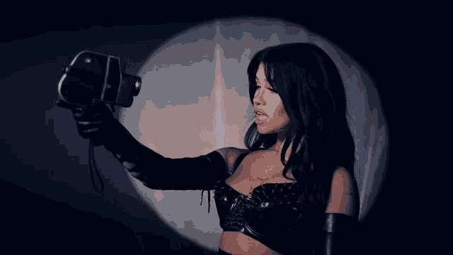 a woman in a black top is holding a camera in a dark room