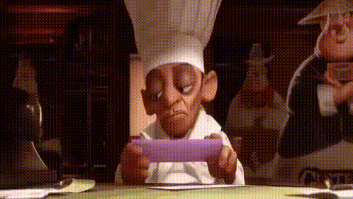 a cartoon chef is sitting at a table with a piece of paper in his hand .