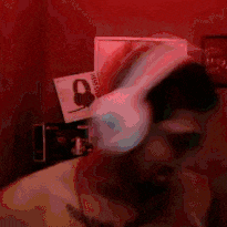 a man is wearing headphones in a dark room with a picture on the wall behind him .