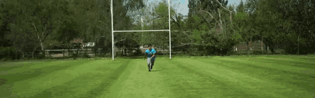 a man in a blue shirt is running on a grassy field