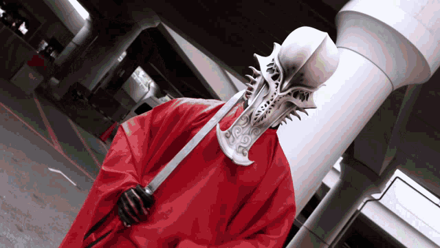 a person in a red cape holding a large sword