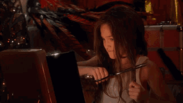 a little girl is cutting her hair with scissors in front of a christmas tree