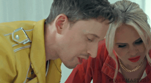 a man in a yellow jacket kisses a woman in a red jacket on the forehead