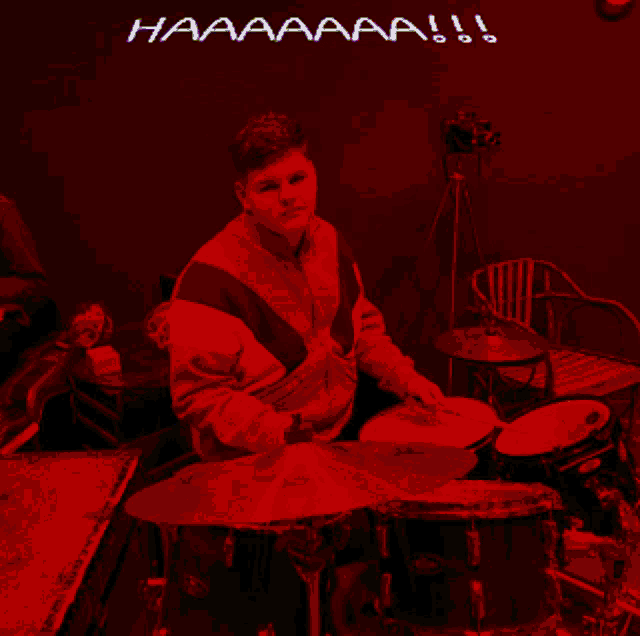 a man is playing drums in front of a wall that says haaaaaaa