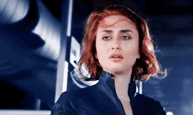 a woman with red hair and a black jacket is standing in front of a building .