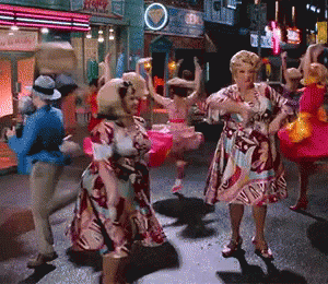 a group of women are dancing on a street in front of a sign that says ' ice cream '