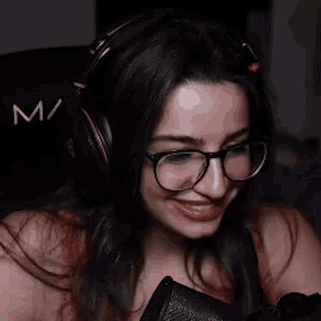 a woman wearing headphones and glasses is smiling and saying eww !