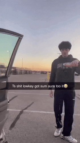 a man is standing in front of a car with a caption that says ts shit lowkey got sum aura too it