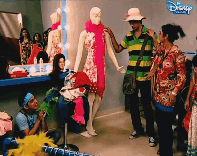 a group of people standing around a mannequin with disney channel written on the bottom right