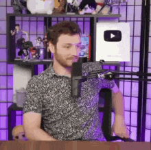 a man with a beard is sitting in front of a microphone in a room .
