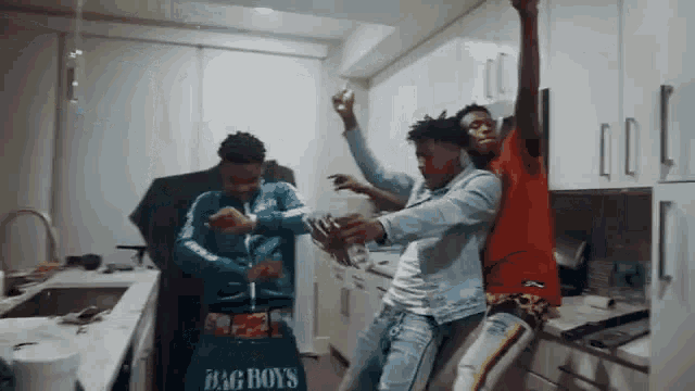 a group of young men are standing in a kitchen dancing .