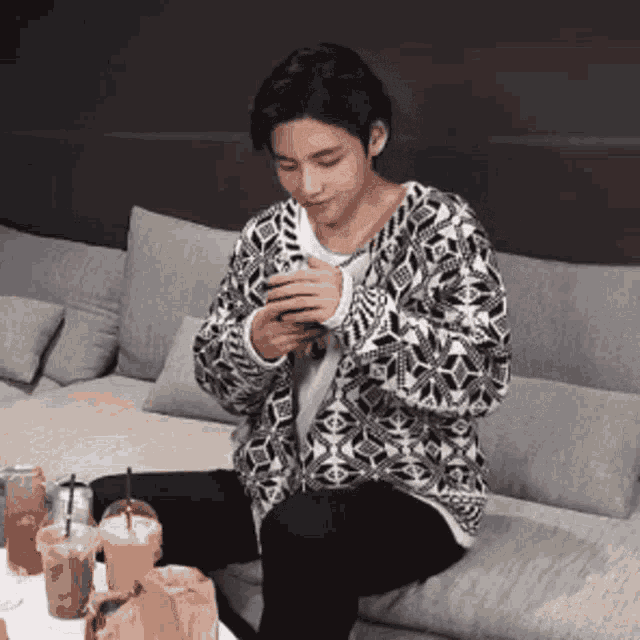 a man is sitting on a couch looking at his phone