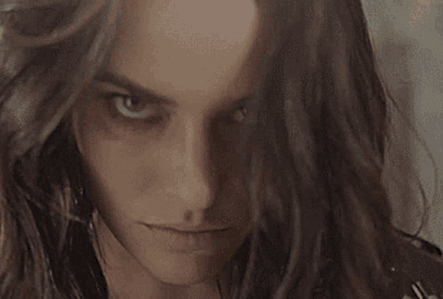 a close up of a woman 's face with a serious look on her face and long hair .