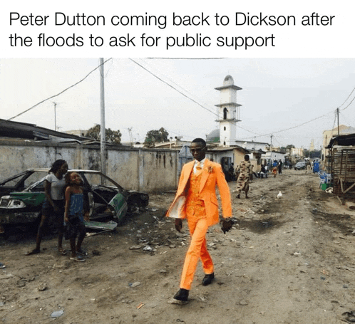 a man in an orange suit walks down a dirt road
