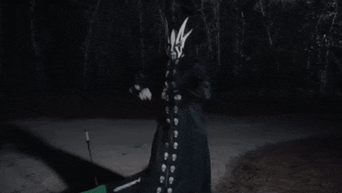 a person with a mask on their face is holding a stick in their hand .