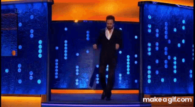 a man in a suit is dancing on a stage in front of a water tank .