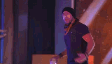 a man in a black tank top is holding a glass in his hand while dancing on a stage .