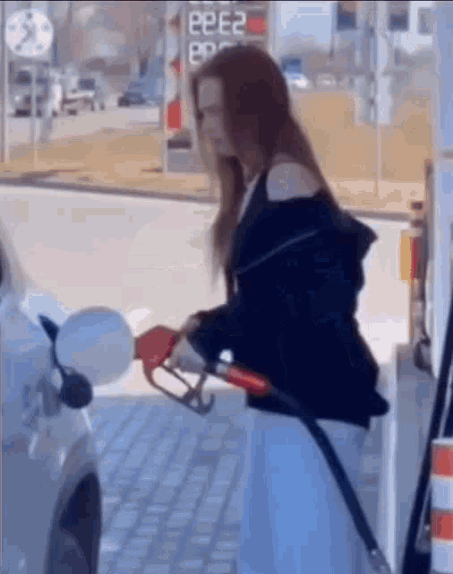a woman is pumping gas into her car at a gas station