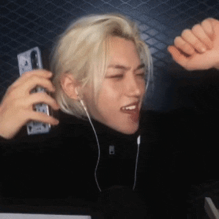a man with blonde hair is wearing earphones and holding a cell phone .