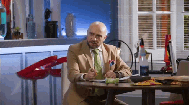 a man in a suit and tie sits at a table with a bowl of chips