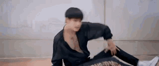 a man is sitting on the floor with his arms outstretched and his shirt off .