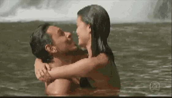 a man and a woman are hugging in the water .