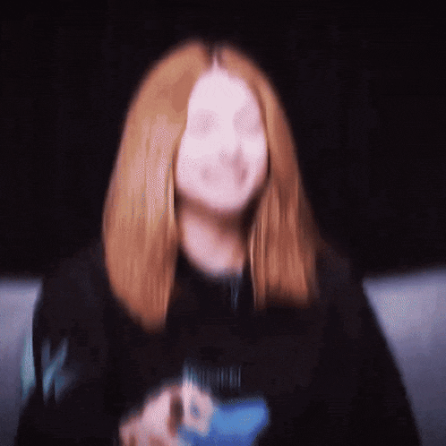 a blurry picture of a woman with red hair wearing a black shirt that says ' nirvana ' on it