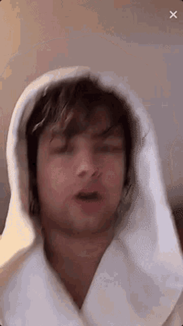 a man in a white robe with a hood on his head is making a funny face .