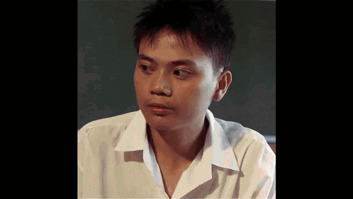 a young man in a white shirt looks to the side