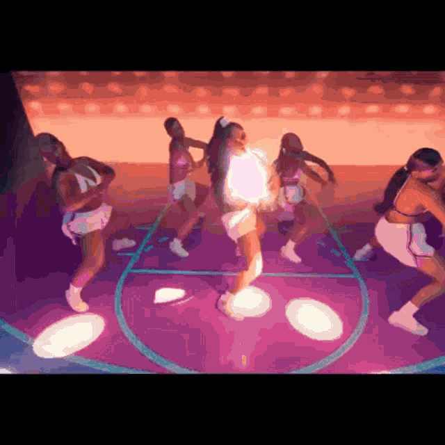 a group of women are dancing on a purple basketball court
