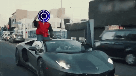 a man in a red jacket is riding in a black lamborghini aventador .