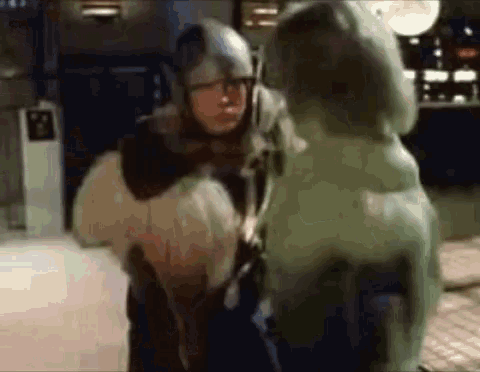 a man in a helmet is standing next to a statue of a man .