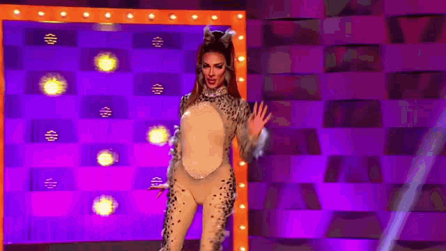 a woman in a leopard costume is standing on a stage with a purple background .
