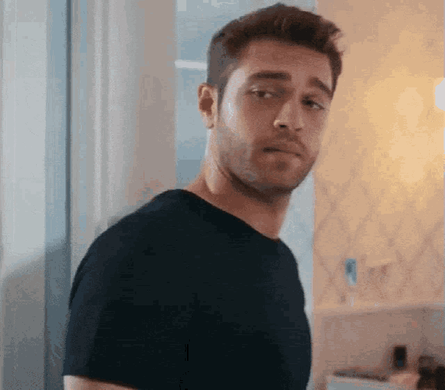 a man in a black shirt is standing in front of a window