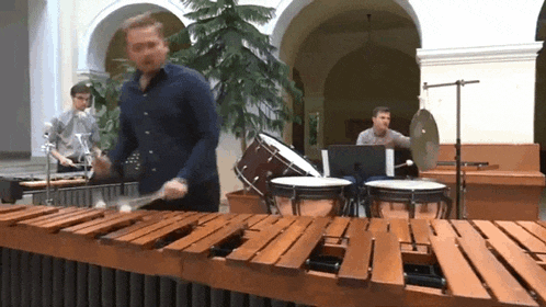 a man in a blue shirt is playing a xylophone