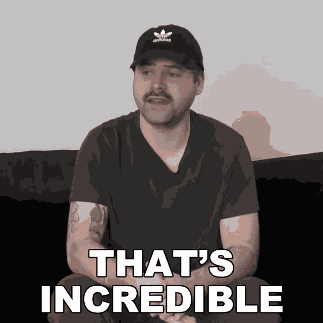 a man wearing an adidas hat is sitting on a couch and says that 's incredible