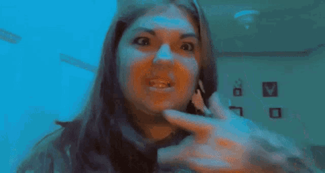 a woman is holding a baby in her arms in a dark room and making a funny face .