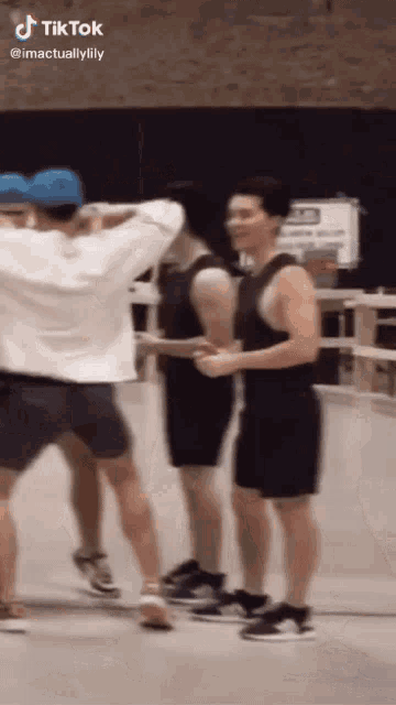 a group of young men are standing next to each other in a gym and dancing .